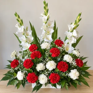 Centro de flores para cementerio con gladiolos blancos y claveles rojos y blancos