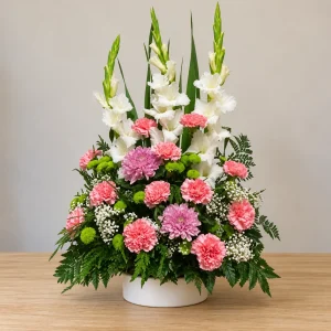Centro de flores para cementerio con gladiolos blancos, claveles rosas, crisantemos rosados y base redonda blanca