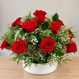 Centro de rosas rojas naturales con paniculata blanca y verdes ornamentales en recipiente blanco